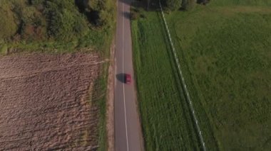 Araba, güzel bir yaz kırsal kesiminde nehir boyunca yol boyunca sürer. Yukarıdan görüntüle