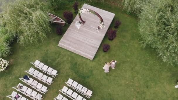 Vista aérea do arco de flor e gramado decorado com cadeiras para cerimônia de casamento na margem do rio — Vídeo de Stock