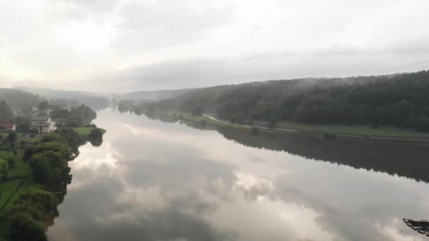 Sparatoria dal drone della pianura alluvionale di un grande fiume con cottage sulla riva e nebbia sopra la foresta — Video Stock