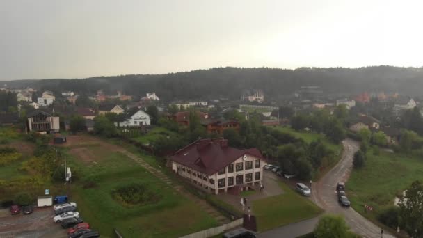 Вид с воздуха на большой элитный коттеджный поселок с особняками на берегу реки и в окружении лесов — стоковое видео