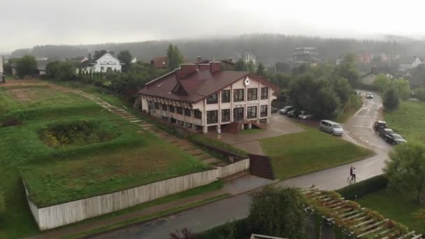 Drohnenabschuss einer großen Villa neben einem Parkplatz in einem elitären Hüttendorf vor der Kulisse eines nebligen Waldes — Stockvideo