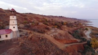 Denizin yamacında bir dron ve gökyüzünün arka planında bir deniz fenerinden çekim yapmak.