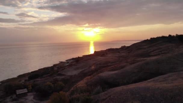 Luftaufnahme der Silhouetten von Hügeln vor dem Hintergrund des Abendhimmels und orangefarbenen Pfad auf dem Meer ab Sonnenuntergang — Stockvideo