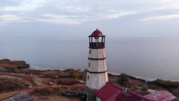 Vista aérea de um farol em uma colina junto ao mar contra o fundo do céu noturno — Vídeo de Stock