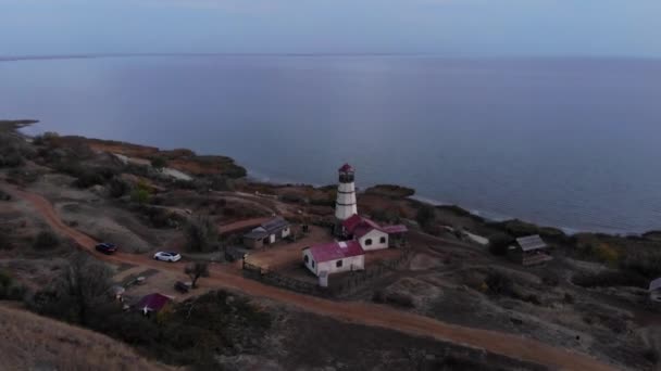 海と空のパノラマと海岸沿いの丘の上に灯台近くの人々を歩くのトップビュー — ストック動画