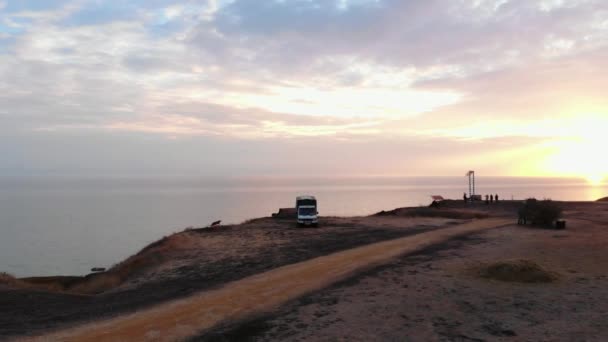 Luftaufnahme eines Autos, das neben einem Lieferwagen auf einem Hügel steht. Meditation und Reflexion Konzept. das Auto steht bei Sonnenuntergang am Strand — Stockvideo
