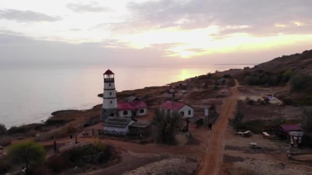 Vista aérea de um farol em uma colina junto ao mar contra o fundo do céu noturno — Vídeo de Stock