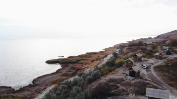 Dron natáčí zblízka maják na kopci u moře a skupinku chodících lidí — Stock video