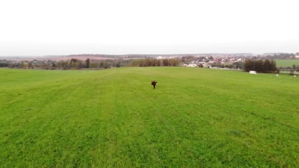 在空中俯瞰着身穿黑衣的少女在绿茵的草地上与乡村风景相映衬的景象。宁静的概念 — 图库视频影像