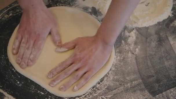 Gros plan d'un chef main dans la cuisine qui roule une base de pizza rkami dans la farine sur la table — Video