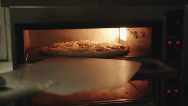 Le chef du café ouvre le four et transforme la pizza avec une spatule en bois — Video