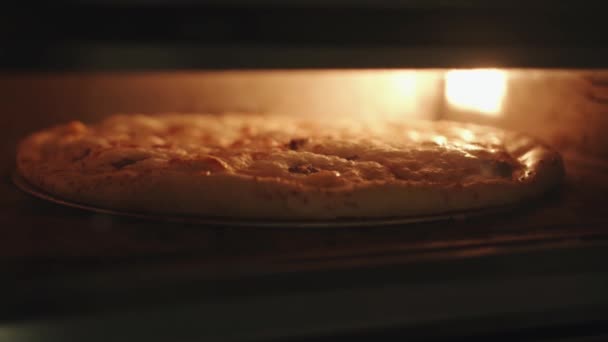 El proceso de cocción de pizza en el horno con iluminación en la cocina de un café y fusión de queso de cerca — Vídeos de Stock