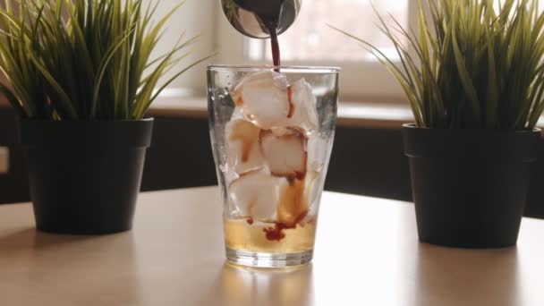 Barista versa il caffè in una tazza di vetro con ghiaccio in piedi su un tavolo in un caffè e fa un cocktail. Primo piano — Video Stock
