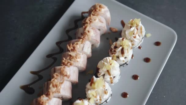 Schöne Bedienung in einem Café von Sushi Maki mit Käsesauce und Speck auf einem Teller mit Tropfen Sauce. Nahaufnahme — Stockvideo