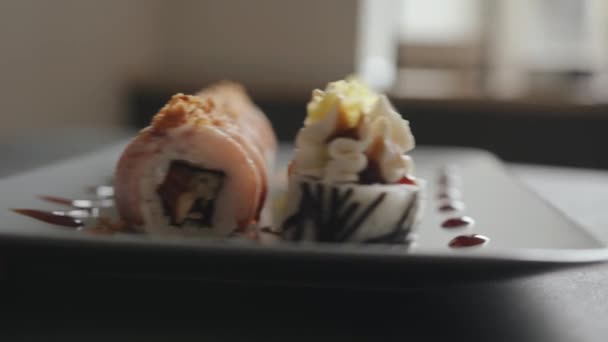 Ein wunderschönes Set von frischem Maki-Sushi mit Käsesauce und Speck, das von allen Seiten in Nahaufnahme präsentiert wird — Stockvideo
