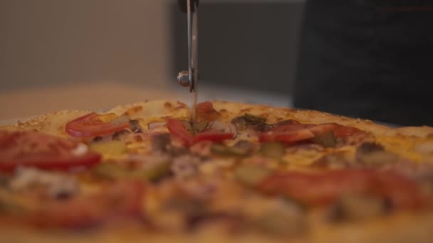 Шеф-повар разрезает томатную пиццу на кусочки специальным круглым ножом. Крупный план — стоковое видео