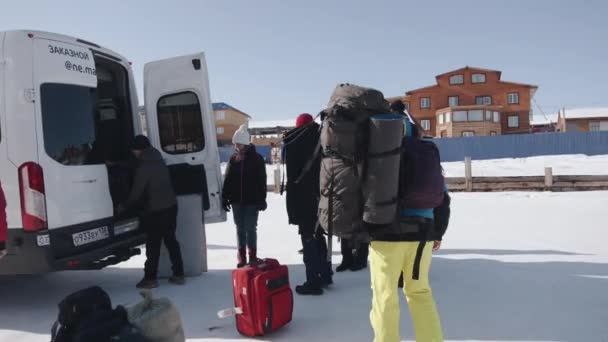 バイカル、イルクーツク地方、ロシア- 2021年3月11日:一緒に旅行している人々のグループと駐車場でミニバスにバックパックと旅行バッグをロードしています — ストック動画