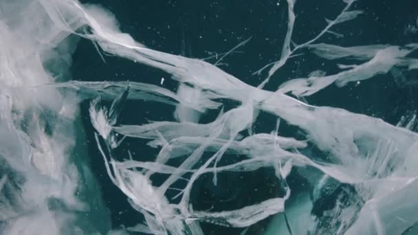 冬の旅行中にバイカル湖の凍結表面の透明な氷の中の亀裂のクローズアップショット — ストック動画