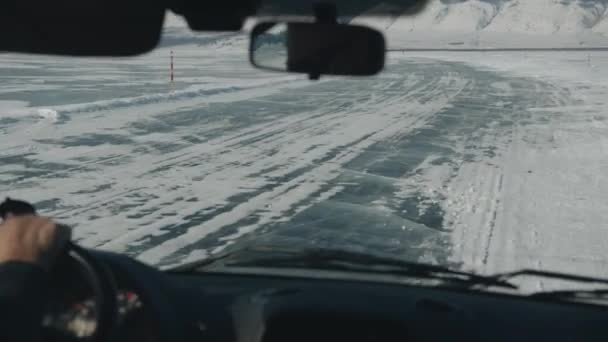 Uitzicht door de voorruit van een auto op mensen en andere auto 's op het bevroren ijs van het Baikalmeer omringd door bergen — Stockvideo