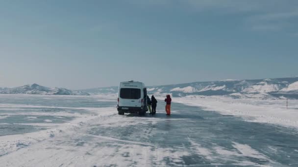 BAIKAL, REGIÓN DE IRKUTSK, RUSIA - 18 DE MARZO DE 2021: Hombres y mujeres abordan un microbús durante un viaje de invierno a través del hielo del lago Baikal y hacia las capas de la isla Olkhon — Vídeos de Stock