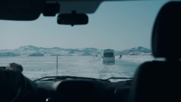 Minibussen rijden langs de ijzige weg van bevroren Baikalmeer tegen de achtergrond van de capes van Olkhon Island — Stockvideo