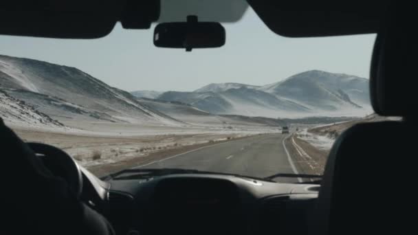Widok przez przednią szybę samochodu na ruchliwej autostradzie otoczonej zaśnieżonymi górami podczas zimowej wycieczki — Wideo stockowe