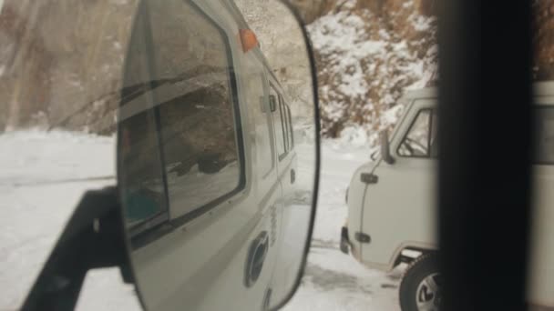 Refleksja w lusterku bocznym minibusa i UAZ stojącego u podnóża góry na zamarzniętym jeziorze Baikal — Wideo stockowe