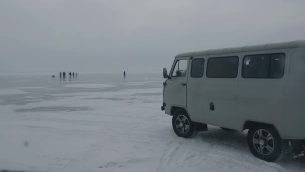 Minibus UAZ przewozi turystów na zamarzniętym lodzie jeziora Bajkał na tle grup ludzi i samochodów — Wideo stockowe