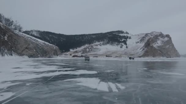 Vinterresa på den kristallklara isen i sjön Baikal vid foten av bergen och utsikt över UAZ minibuss — Stockvideo