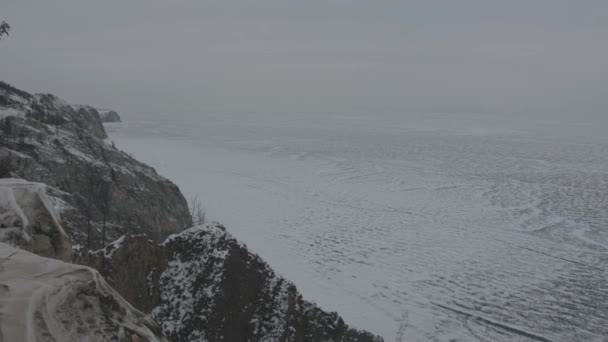 안개낀 겨울 날씨에 눈덮인 바이칼 호수의 높은 해안 바위에서 바라본 모습 — 비디오
