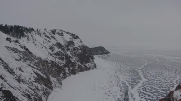 Una vista desde la montaña hasta los promontorios boscosos cerca del congelado lago Baikal en un día nublado de invierno — Vídeo de stock