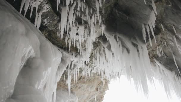 凍った湖の海岸にあるオルホン島の洞窟の天井から吊るされたつららの列の絶景バイカル — ストック動画