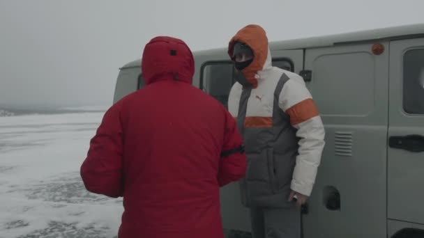 Baikal, regio Irkoetsk, Rusland - 18 maart 2021: Toeristen stappen in UAZ minibussen na een excursie langs de kust van het Baikalmeer bedekt met ijs. Langzame beweging — Stockvideo