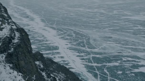 Uçurumdan yüzeye bak. Baykal Gölü 'nün kristal berrak buz desenleri ve ayaktaki arabalarla. — Stok video