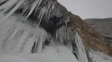 Buz kaplı duvarlar ve Baykal Gölü kıyısındaki Olkhon Adası 'nın kayalık kayalıklarından sarkan bir sürü buz sarkıtı.