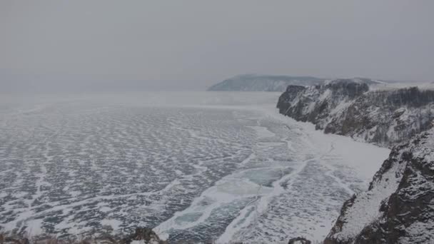 A stunning panorama of the frozen Lake Baikal, surrounded by mountains and islands among cracks and patterns on the ice — Stock Video