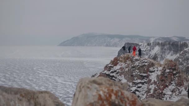 Un grupo de personas camina a lo largo de un camino en la cima de las montañas alrededor del lago congelado Baikal — Vídeos de Stock