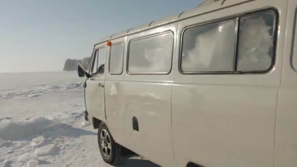 Baikal, Irkutsk Region, Ryssland - 18 mars 2021: UAZ minibuss lämnar tältlägret på den frusna isen vid sjön Baikal nära ön Olkhon en solig vinterdag — Stockvideo