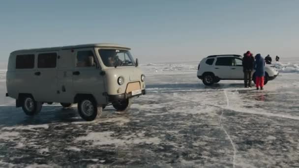 Baikal, Region Irkutsk, Russland - 18. März 2021: UAZ-Kleinbusse bringen Gruppen von Menschen über das gefrorene Eis des Baikalsees in Zeltlager für extreme Übernachtungen — Stockvideo