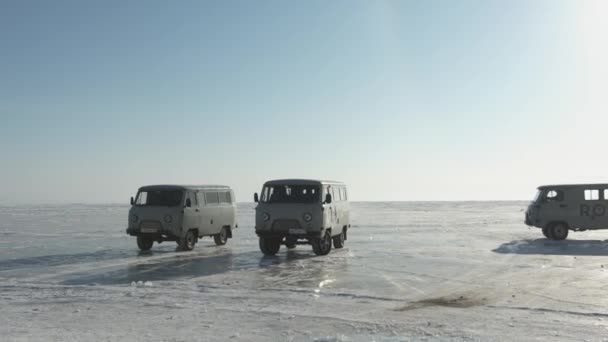 바이칼, 러시아 이르쿠츠크 지역, 2021 년 3 월 18 일: 러시아 의고 전기 미니버스 UAZ 가바 이 칼 호수의 얼음 위에서, 맑고 푸른 하늘을 배경으로 한 줄로 서 있다 — 비디오