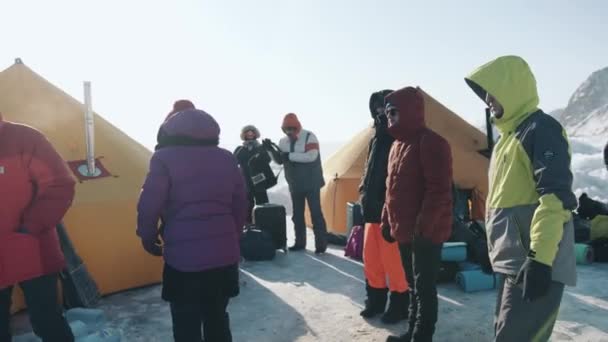 Baikal, regio Irkoetsk, Rusland - 18 maart 2021: Een groep toeristen in een tentenkamp op het ijs van het Baikalmeer met spullen om de nacht door te brengen in het kamp. Extreem toerisme — Stockvideo