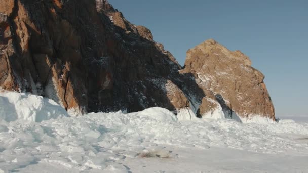 Uma bela vista das montanhas rochosas na costa do Lago Baikal com gelo floes e neve ao pé em um dia ensolarado de inverno — Vídeo de Stock