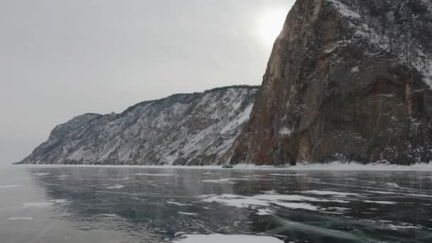 Bella vista sulle montagne innevate sulla riva del lago ghiacciato Baikal e auto ai piedi della scogliera — Video Stock