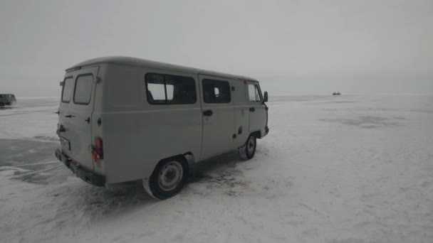 Minibusy UAZ przewożą turystów po zamarzniętym lodzie jeziora Bajkał. Ekstremalne podróże zimowe — Wideo stockowe