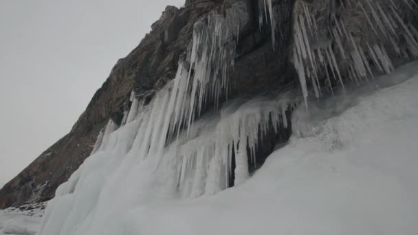 Stunning view of the rocky mountains on the shores of Lake Baikal with huge hanging icicles and icy foothills — Stock Video