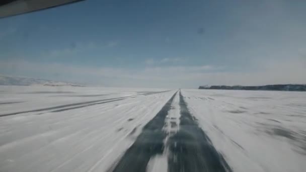 El coche conduce a alta velocidad en el hielo transparente del lago Baikal en un día soleado. pov de mano de la cámara — Vídeos de Stock