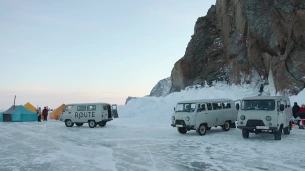 Baikal, Wilayah Irkutsk, Rusia - 18 Maret 2021: Rekreasi musim dingin yang ekstrim di sebuah tenda berkemah di tepi Danau Baikal dan berdiri di kaki tebing UAZ minibuses — Stok Video