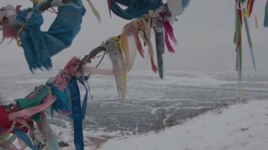 Arzular ağacında renkli hadak kurdeleleri ve buz kaplı Baykal Gölü 'nün oradaki tepeden inen bir grup insan.