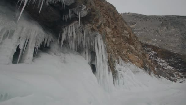 Met ijs bedekte muren en veel ijspegels die hangen aan de rotsachtige kliffen van Olkhon Island aan de oevers van het Baikalmeer — Stockvideo