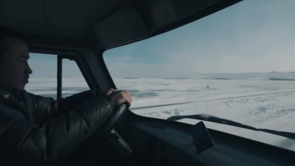 Baikal, Irkutskin alue, Venäjä - 18. maaliskuuta 2021: Buryatin kansalainen, joka ajaa minibussia, kuljettaa turisteja Baikal-järven lumen peitossa — kuvapankkivideo